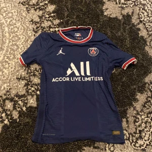 Blå PSG fotbollströja med Messi 30 - Säljer en blå PSG fotbollströja från Jordan med Messi och nummer 30 på ryggen. Tröjan har korta ärmar och vita, röda och blå detaljer vid krage och ärmslut. Perfekt för fotbollsfans!