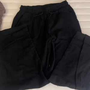 Svarta linnebyxor  - Säljer ett par svarta linnebyxor med resår och snörning i midjan. Byxorna har en loose passform och är perfekta för en avslappnad stil.