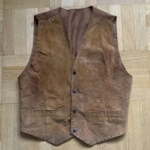 Brun väst med knappar - Brun väst med knappar framtill och justerbar på baksidan! Som man ser på första bilden har den lite missfärgningar på framsidan