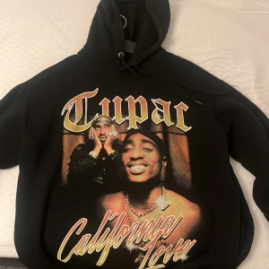 Tupac hoddie - En hel svart hoddie med tupac tryck på framsidan. Sitter lite oversize, perfekt inför hösten. Tröjan går att stila både för män och kvinnor. Ena snöret har skadats o därför säljer jag hoddin billigare än vad jag köpt den för.