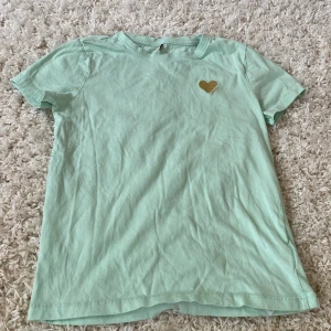 Grön t-shirts från only  - Oamvänd stolek 146/152 från only är grön men ett guld glittrigt hjärta 