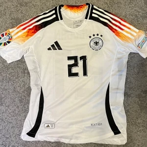 Tyskland EM 2024 - Tysklands hemmaställ under EM 2024 med Gundogan 21 på ryggen. Tröjan är i nyskick och är knappt använd. Den är i ”spelar version” vilket betyder att den sitter lite tajtare, så den passar storlek S-M. Pris kan diskuteras. 