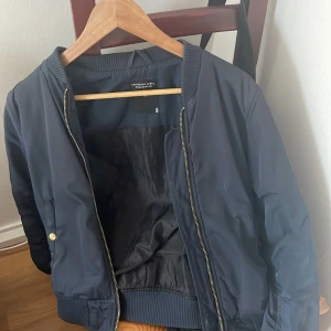 Marinblå bomberjacka från The Black Label Collection - Säljer en snygg marinblå bomberjacka från The Black Label Collection. Jackan har en dragkedja framtill och ribbade muddar vid ärmslut och nederkant. Perfekt för höst och vår! 🖤