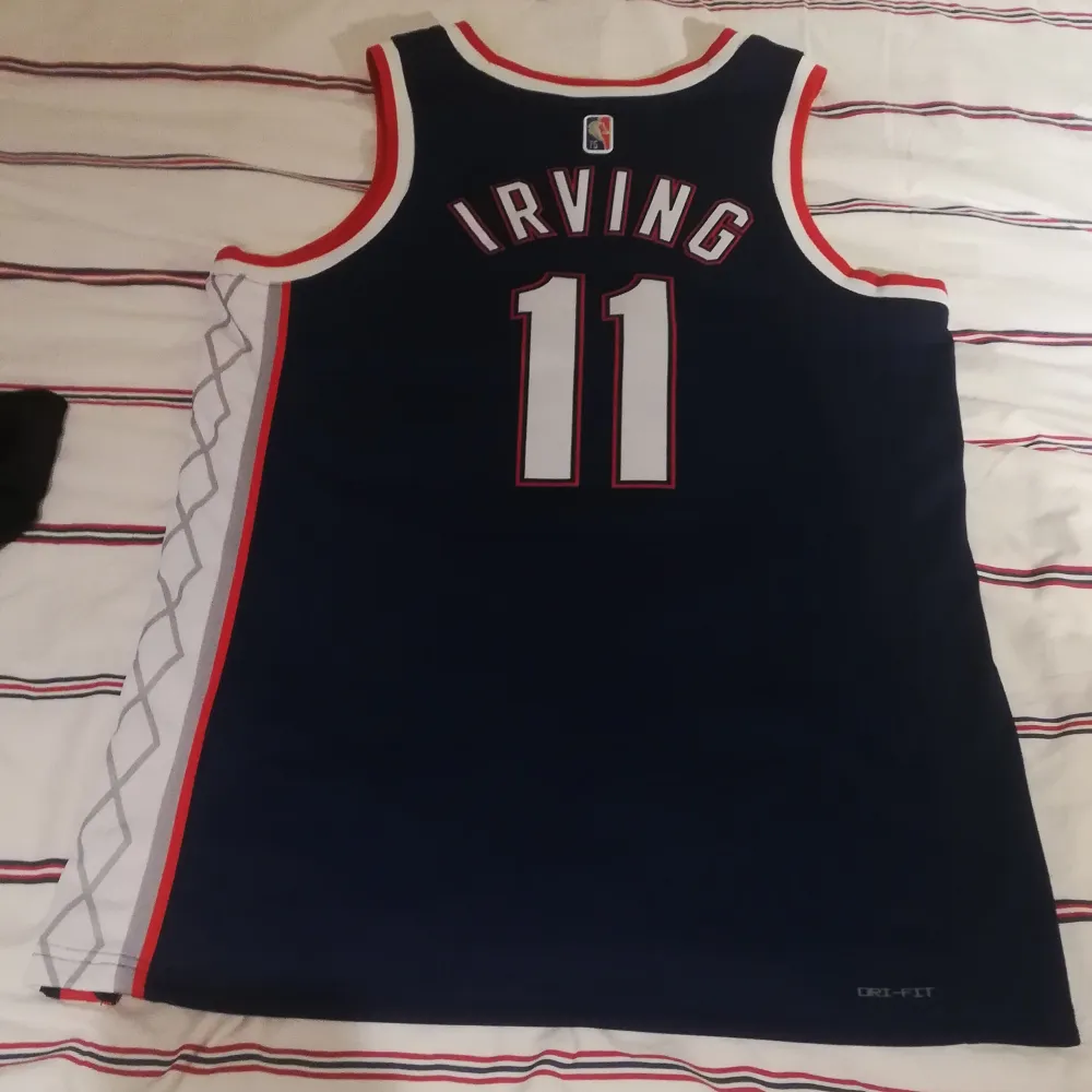 Basketlinne med i storlek L med NBA-laget Brooklyn Nets. Kyrie Irving (#11 på ryggen). Linnet är i gott skick och såklart original. Passar bra på mig som är 1,85 och något bredaxlad. . Sportswear.