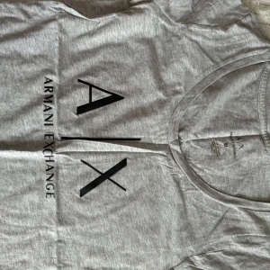 Grå t-shirt från Armani Exchange och flera märken  - Snygg grå t-shirt från Armani Exchange och flera olika märken med stort svart tryck på framsidan. Perfekt för en casual look.