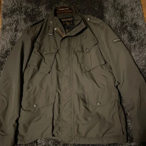 Woolrich Fieldjacket - Säljer en tvärfet, olivgrön fieldjacka från Woolrich. Jackan är i helt nytt skick och perfekt inför våren! NYPRIS 5000+ kr. Jackan är i S/M, sitter bra på mig som är runt 183. Hör av er vid bättre bilder eller pris