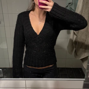 Svart stickad tröja - Säljer en svart stickad tröja med v-ringning. Tröjan har långa ärmar och en ribbad design som ger en snygg passform. Perfekt för kyligare dagar.