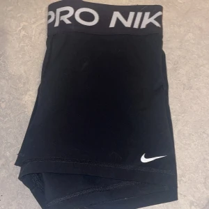 Svarta träningsshorts från Nike Pro - Säljer ett par svarta Nike Pro träningsshorts med Dri-FIT-teknologi. De har en elastisk midja med Nike-logga och är perfekta för intensiva träningspass. Shortsen är designade för att ge en tight passform och maximal rörelsefrihet. jag har sett lappen men man kan bara klippa av det säljs för de är för stora