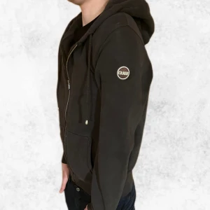 Mörkgrå zip hoodie från Colmar - Säljer en stilren mörkgrå zip hoodien från Colmar med dragkedja och justerbar huva. Det är i mycket bra skick och är endast använd ett par gånger. Den är i storlek L men sitter snarare som en M. Modellen är 183 cm.