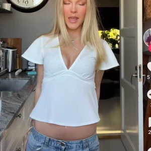 Vit v-ringad blus med knytband - Snygg vit blus med v-ringning och korta ärmar. Blusen har ett knytband i ryggen som ger en fin passform.