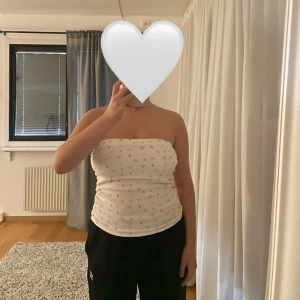 Vit tubtopp med fjärilsmönster från Djerf Avenue - Säljer en söt vit tubtopp från Djerf Avenue med ett färgglatt fjärilsmönster. Perfekt för en avslappnad och stilren look. Toppen är i storlek M och har en mjuk och bekväm passform.