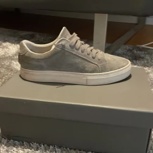 Grå sneakers från Vagabond - Snygga grå sneakers från Vagabond i mocka med snörning. Perfekta för en stilren look med en bekväm passform. Skorna har en vit sula som ger en fräsch kontrast till det gråa.