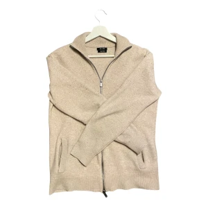 Beige kofta med dragkedja - Snygg beige kofta från massimo dutti med dragkedja framtill. Den har långa ärmar och ribbade muddar vid ärmslut och nederkant. Perfekt för lager-på-lager under kyligare dagar. Riktigt fet och passar dig runt 170-175 