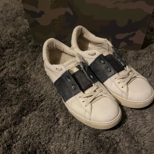 Valentino Opens - Säljer ett par snygga Valentino Open skor i färgen vit och navy blå med en unik sida. Skorna är använda men i fortsatt bra skick. Köpta av Victor Hansson, kom dm för kvitto och betalningsbevis. Skorna är i storlek 41 men passar även 42. EJ originalbox, dustbag medföljer vid snabb affär! Går självklart att diskutera pris!