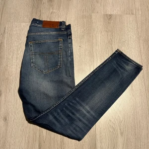 Mörkblå jeans från Tiger of Sweden - Snygga mörkblå jeans från Tiger of Sweden med klassisk femficksdesign. De har en knappgylf och är tillverkade i ett slitstarkt denimtyg. Perfekta för en stilren look.