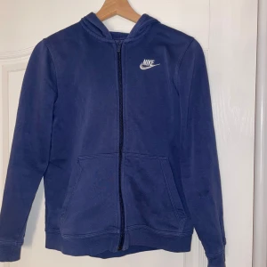 Blå hoodie från Nike - Säljer en blå hoodie från Nike med dragkedja och huva för att den tyvärr har blivit för liten. Hoddien är från kidsbrandstore så storleken står som L/147-158 passar bra för xs och storlek 158!💓