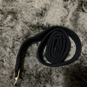 Svart flätat bälte - Snyggt svart flätat bälte med en stilren design. Perfekt för att ge en extra touch till din outfit. Bältet har en klassisk spänne i silverfärg som ger en elegant kontrast.