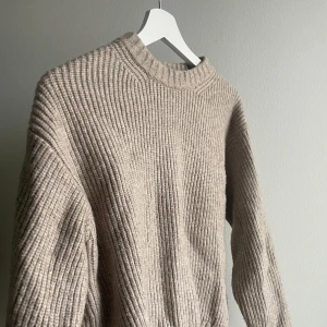 Beige stickad tröja - Säljer en stilren beige stickad tröja med ribbad design. Tröjan har långa ärmar och en rund halsringning, perfekt för kyligare dagar. Passar bra till både jeans och kjol. Ett måste i garderoben för en avslappnad och trendig look. Från HM, använd fåtal gånger! 