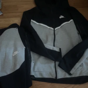 Säljer nike tech tracksuit svartgrå - Säljer min gråsvarta nike tech tracksuit inte använd så mycket, pris kan diskuteras och man kan även köpa byxorna eller fleecen enskilt men priset är både fleecen och byxorna. Byxorna är storlek M och fleecen är storlek S!