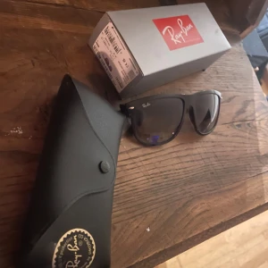 Ray-Ban boyfriend - Snygga svarta solglasögon från Ray-Ban med klassisk design. De har en robust båge och mörka linser som ger ett stilrent intryck. Perfekta för soliga dagar och kommer med ett praktiskt fodral för förvaring.
