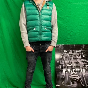 Moncler väst - Säljer en snygg grön dunväst från Moncler med dragkedja och två fickor framtill. Perfekt för lager-på-lager under kyligare dagar. Västen har en stilren design och är lätt att matcha med olika outfits. Storlek 3 (xs)