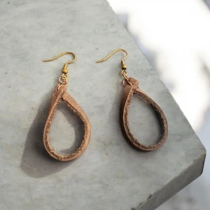 Bruna läderörhängen med guldfäste - Snygga örhängen i brunt läder med en droppformad design. De har guldfärgade krokar som ger en elegant touch. Perfekta för att ge en naturlig och stilren look.