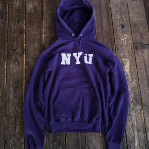 Lila hoodie från Champion - Säljer en snygg lila hoodie från Champion med trycket 'NYU' i vitt på bröstet. 