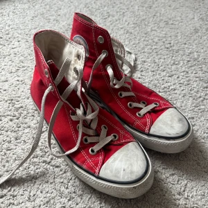 Röda Converse All Star sneakers - Klassiska röda Converse All Star sneakers i hög modell med vita snören och tåhätta. Skorna har den ikoniska logotypen på sidan och en vit sula med svart rand. Storlek 40 (små i storlek, passar mig som har 39). 😊