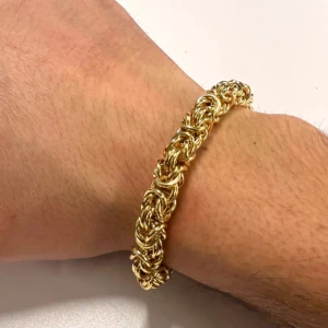 Guldarmband med flätad design - Elegant guldarmband med en intrikat flätad design. Perfekt för att ge en lyxig touch till din stil. Armbandet har en robust och glänsande finish som fångar ljuset vackert. Det är 19cm lång och 8mm bredd, det är äkta 18k guld planterat och rostfritt stål vilket betyder att du kan bada och duscha med det hur mycket du vill utan att det händer något med den 