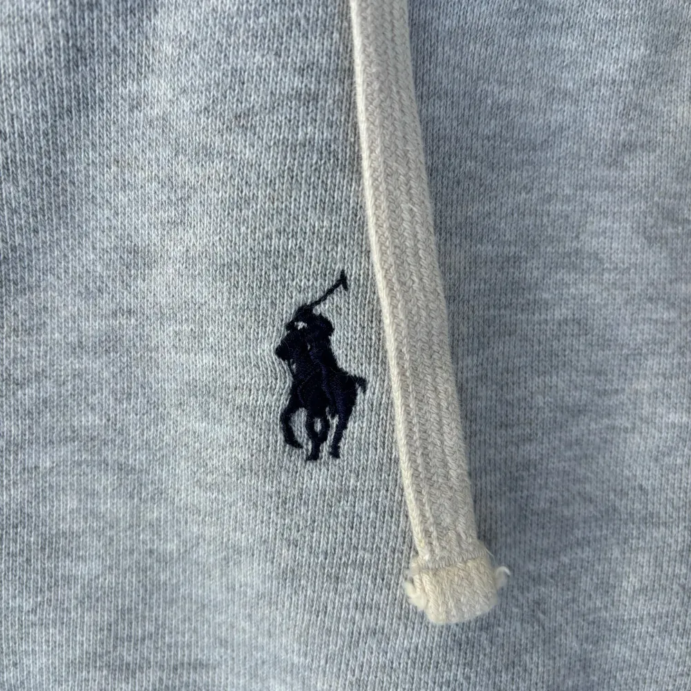 Säljer en stilren och bekväm grå hoodie från Polo Ralph Lauren. Den har en dragkedja framtill och en klassisk broderad logga på bröstet. Perfekt för både höst och vår, med en normal passform och mjukt material som håller dig varm. Huvan har justerbara snören för extra komfort. Passar perfekt till vardags eller en avslappnad dag ute.. Tröjor & Koftor.