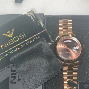 Nibosi klocka - Helt ny oanvänd Nibosi klocka, säljes då jag inte använder klockor.  Man kan göra denna klocka till mindre storlekar då man lätt kan avlägsna länkarna, och lätt att sedan sätta på dom igen.  Plasten kvar på klockan.  Köptes för 1195kr