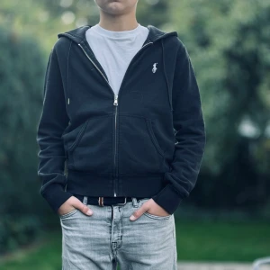 Svart hoodie från Polo Ralph Lauren - Säljer en snygg svart zip hoodie från Polo Ralph Lauren i storlek M. Perfekt för en casual look och passar till alla tillfällen.  Superbekväm att ha på sig, perfekt för höst och vår. Skick 8/10. Skriv privat för intresse om fler bilder.