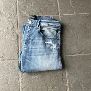 Replay jeans - Säljer nu dessa populära replay jeans med slitningar! Jeans har ett väldigt fint skick eftersom de endast är använda 2-3 gånger! Modellen är grover och har en slim passform och storleken är 32/34!  Nypris är 2000 säljer den endast för 800!