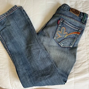 Vintage jeans med detalj på fickor - Super fina vintage jeans fyndade utomlands!! Unika med broderi på fickor samt grön och orange tråd. En fläck på vänster knä. Älskar dessa!! 