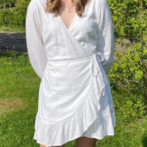 Vit sommarklänning  - Drömmig vit omlottklänning i linnetyg! Använd ca 3 gånger. På de två sista bilderna är den knyten lite konstigt vilken ger den en udda form. Köpt för 450💗
