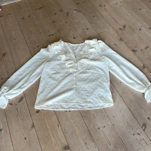 Vit blus - Vit blus med knappar, spets och volang.