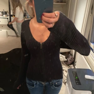 Svart ribbad kofta med dragkedja - Säljer en snygg svart ribbad kofta med dragkedja framtill. Den har en v-ringad design och långa ärmar. Märket är Stefanel, tyvärr står det ingen storlek men gissar på S
