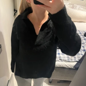 Svart tröja med krage - Säljer en stilren svart tröja med krage. Den är perfekt för både vardag och lite mer uppklädda tillfällen. Tröjan har långa ärmar och en bekväm passform. Supermjuk och skön att ha på sig. Slits på sidorna!