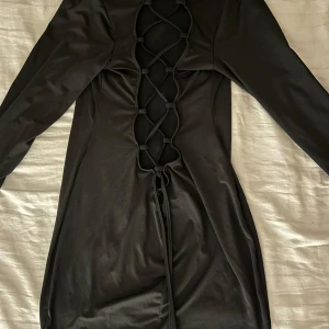 Klänning med ryggknytning - Fin svart klänning med ”halvöppen” rygg med snörning! Går att använda omvänt så snösningen kommer framtill! Vet ej nypris eller märke därav lågt pris!