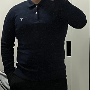 GANT Pikétröja Mörkblå - Säljer en stilren och klassisk mörkblå pikétröja från GANT i storlek S. Tröjan har knappslå och den ikoniska GANT-loggan broderad på bröstet. Väldigt bekväm och passar både till vardag och mer uppklädda tillfällen. Använd ett fåtal gånger