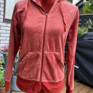 Rostfärgad Hoddie B.young M - Hoddie med dragkedja, del saknas på blixtlåslöpare-se bild! 80% bomull, 20% polyester Längd: 62cm Armhåla till armhåla: 51cm  Inga bilder när den sitter på mig! Katter finns i hemmet