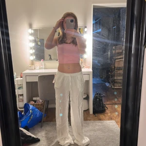 Vita byxor med dragsko - Säljer ett par vita linnebyxor, raka och low Waist. Helt oanvända och prislappen finns kvar. Dom sitter perfekt i midjan men för långa för mig, jag är 159 och skulle säga att dom passar för nån som är 161+. Dom är också ifrån Nelly!💓. Skriv för pris