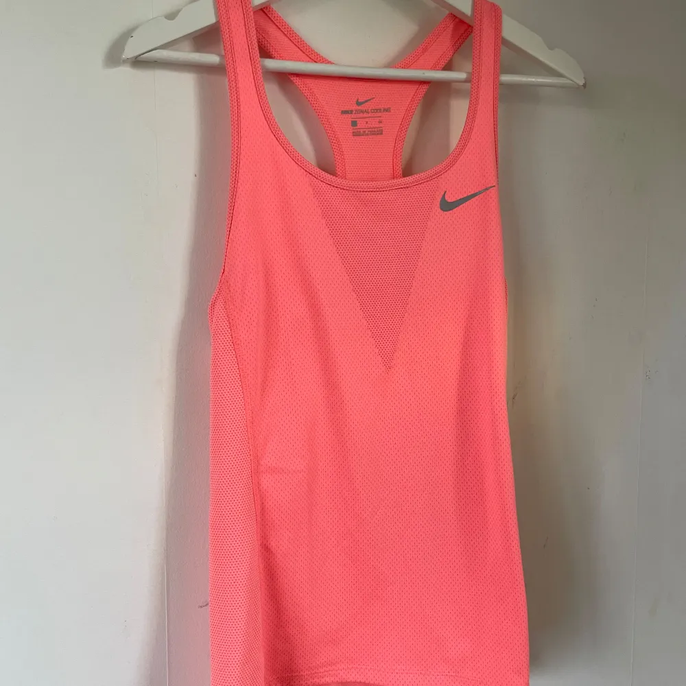 Säljer ett snyggt rosa träningslinne från Nike med deras Zonal Cooling-teknologi. Linnet är ärmlöst och perfekt för träning, med en tight passform som ger bra stöd. Det har en rund halsringning.  Perfekt för gymmet. Toppar.