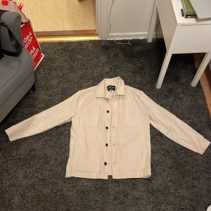 Mads Nørgaard overshirt - Säljer en beige/benvit overshirt från Mads Nørgaard i modell ”Canvas Somme Shirt” i storlek S. Overshirten är endast använd ett fåtal gånger men har en liten slitning på framsidan som framgår av bilden. Nypris 2399 kr