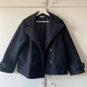 Svart Design by Si kappa  - Säljer en super fin svart kappa i storlek Xs/S  ifrån Design by Si.  Den är använd och har få  defekter så som små repor på vissa av knapparna men inte så mycket mer än så då den är i bra skick. Det finns även en extra knapp med jacka i behov. 💕