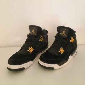 Svarta och gula Nike Air Jordans - Säljer ett par snygga Jordans 4 retro royalty i svart och gulda detaljer, samt en vit sula som ger en cool kontrast.