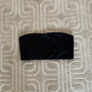 Bandeu - Svart bandeu i glansigt material. Insydd vaddering, så du behöver ingen bh under. Endast provad, aldrig använd.