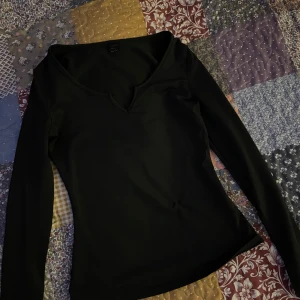 Svart långärmad topp - Säljer en stilren svart långärmad topp i mycket bra skick. Den har en snygg v-ringning . Materialet känns mjukt och bekvämt mot huden. Har ett litet hål som jag sytt igen på framsidan