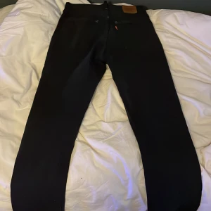 Svarta jeansbyxor Levis 501 - Säljer ett par svarta jeansbyxor i bra skick. De har en klassisk design med knapp och dragkedja framtill.