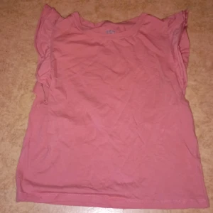 Rosa topp från 157 - Säljer en rosa topp från 157 i storlek S. Toppen är i bomull och har volangdetaljer vid ärmarna. Den är i acceptabelt skick med några fläckar. Tror det borde gå bort i tvätten men ingen man märker av och har aldrig tänkt på att dom varit där